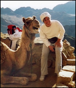 Donna Lozito sitting with camel on mountain